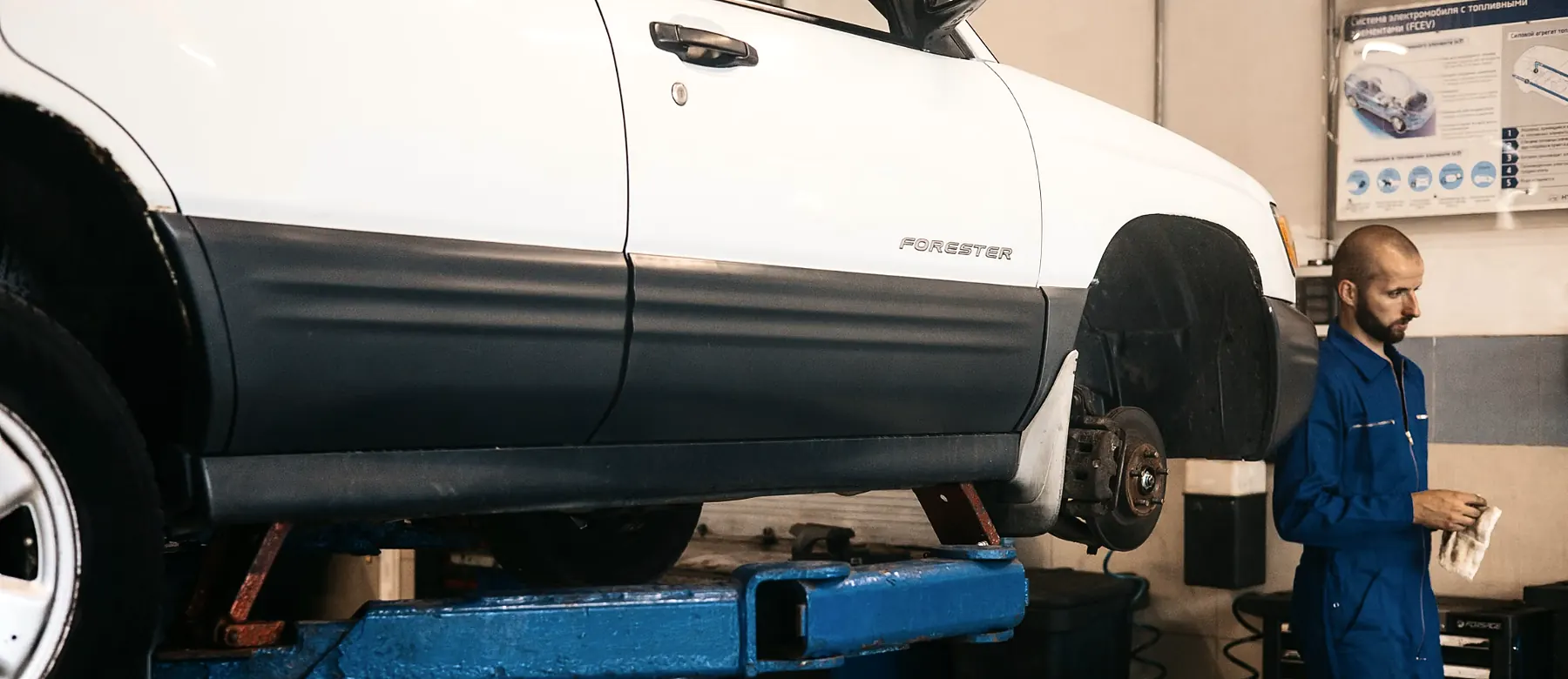 Mechanic working beside a car raised on a lift in a repair shop