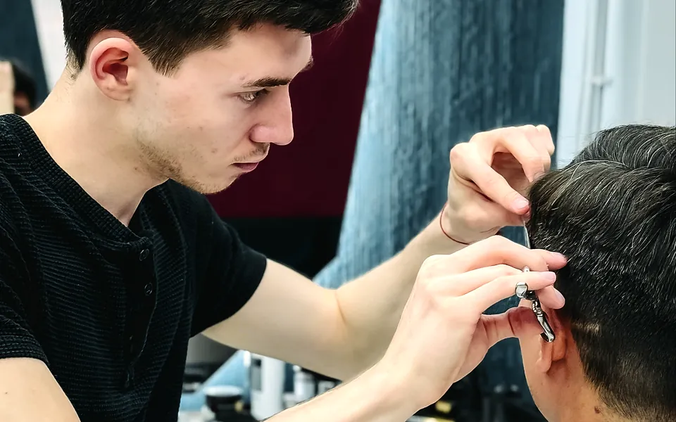Barber trimming a client's hair with scissors