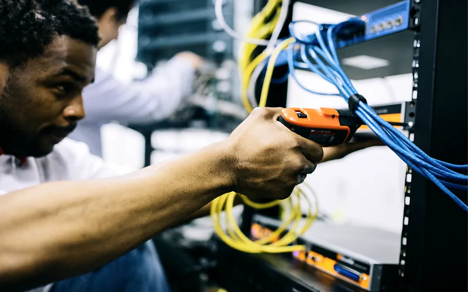 IT technician connecting network cables in a server rack