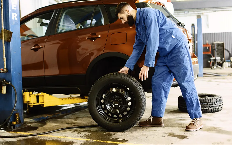 Mechanic checking a tire on an SUV in a service bay