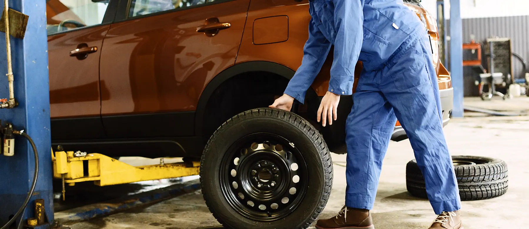 Mechanic checking a tire on an SUV in a service bay