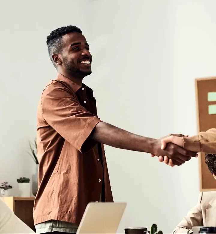 Startup founder shaking hands with a partner during a team meeting