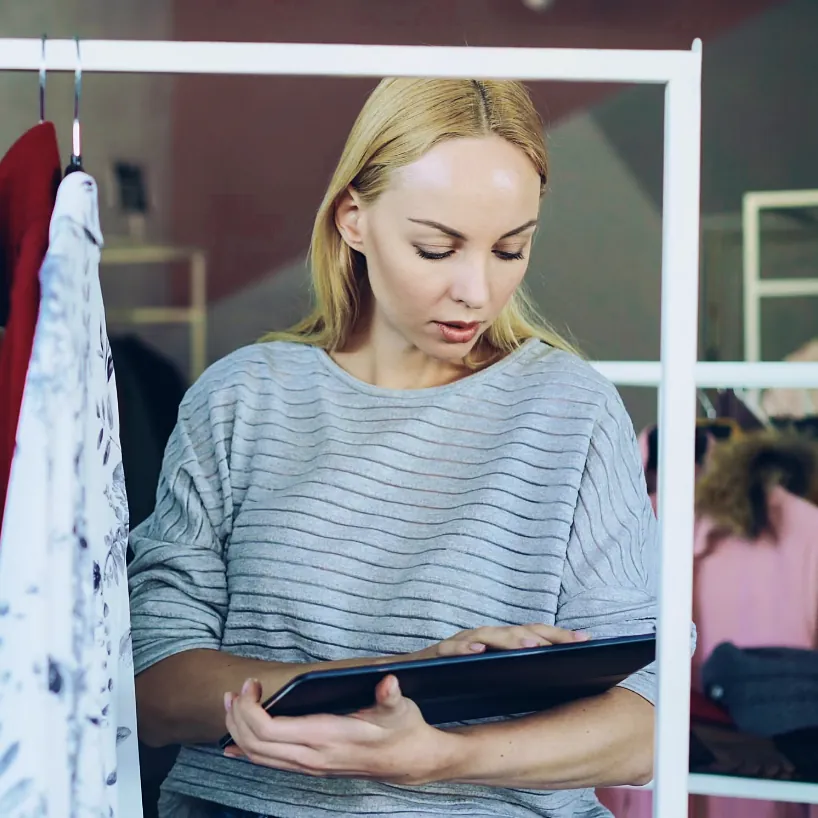Boutique owner reviewing stock levels on a tablet beside a clothing rack